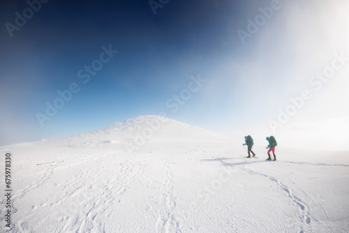 climbers climb the mountain in the snow. Winter mountaineering. two girls in snowshoes walk through the snow. mountaineering equipment. hiking in the mountains in winter. © zhukovvvlad