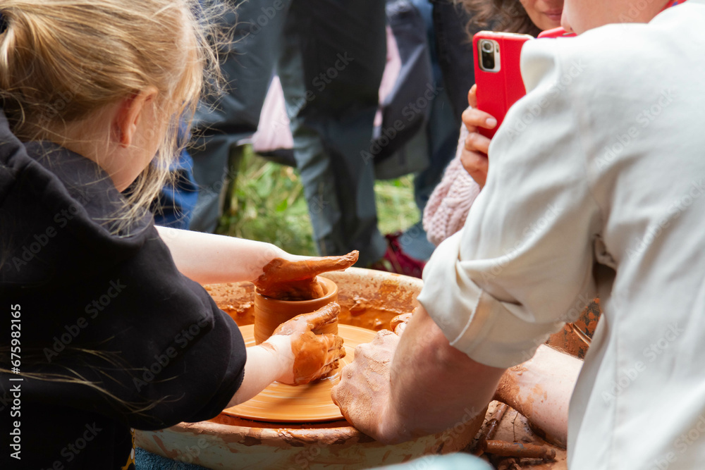 Obraz premium Pottery training. Rotating a clay pot on a machine. Hands knead clay. Making a clay pot.