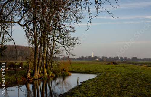 The countryside of Groningen, the Netherlands. The beautiful blue and white tower of the Mariakerk in Uithuizermeeden on the horizon. photo
