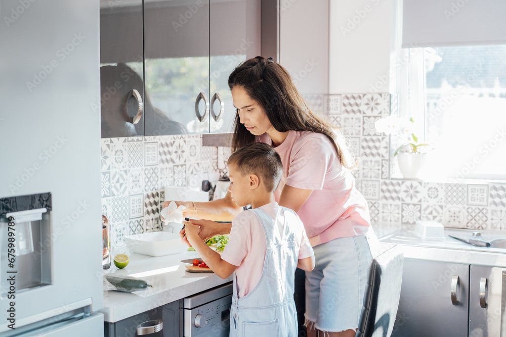 Caring young Mother putting a plaster on child finger with wound on from a cut by kitchen knife. First aid in case of small domestic injury. Children's injuries at home. Negligence in cooking at home