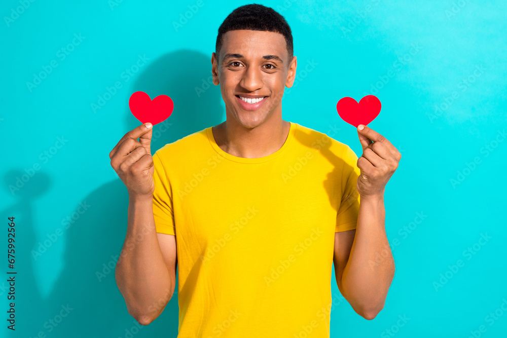 Photo of young lovely boyfriend wear yellow t-shirt hold paper symbol heart sympathy anniversary isolated on aquamarine color background Photo of young lovely boyfriend wear yellow t-shirt hold paper symbol heart sympathy anniversary isolated on aquamarine color background