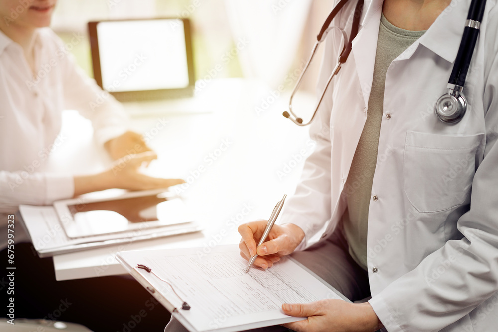 Doctor and patient view. Female physician is filling up a records from opposite a woman having a medical examination. Medicine concept