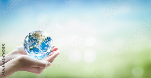Human hand holding globe on blurred green and blue nature background. Elements of this image furnished by NASA photo