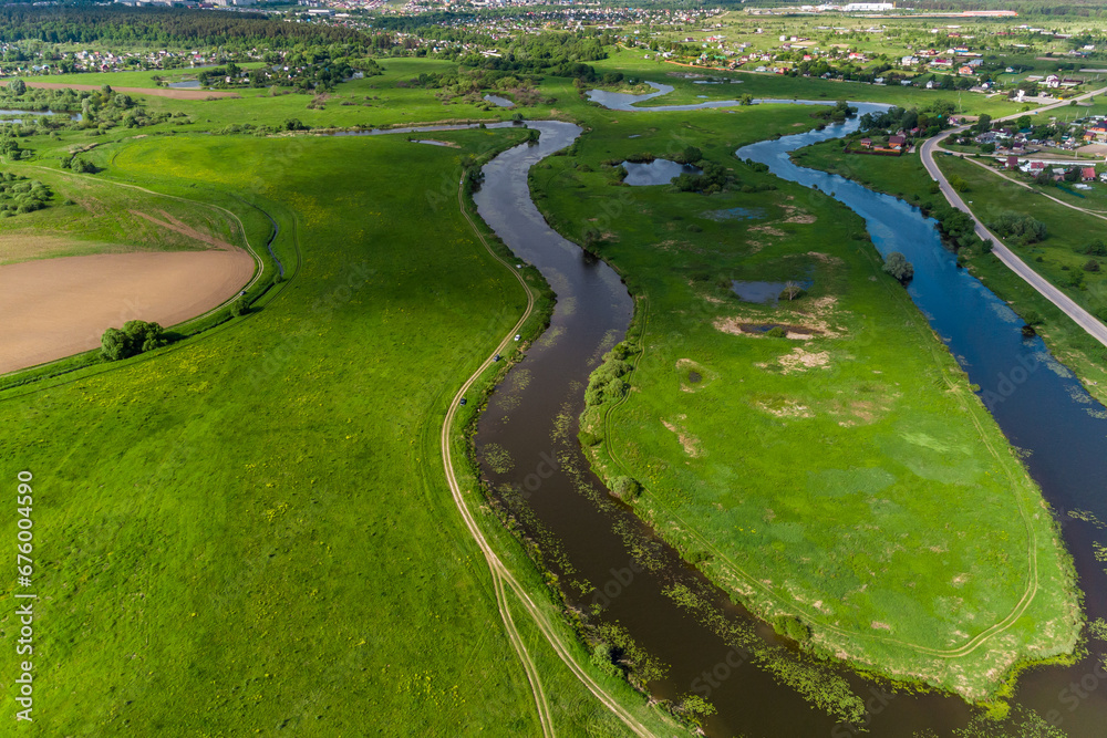 Landscape from the air, an elongated and winding river bed among green fields. Old lake Ogublyanka, Kaluga region