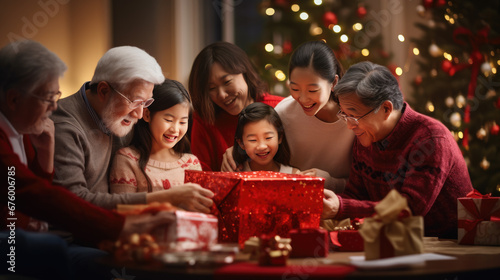 A delighted family share a heartwarming moment while unwrapping a Christmas gift against the backdrop of a glowing festive tree.