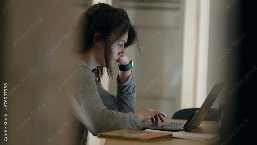Candid woman browsing internet on laptop computer at night. Person staring at scren working late at night - obrazy, fototapety, plakaty 