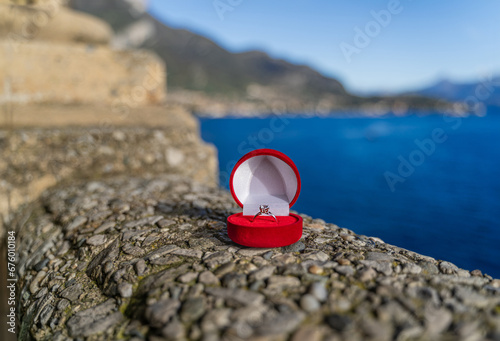 Engagement ring in a red velvet box for a marriage proposal while traveling around Europe and the world - in Italy on Lake Como