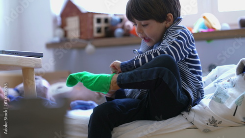 Tableau sur toile Child putting on sock seated by bedside