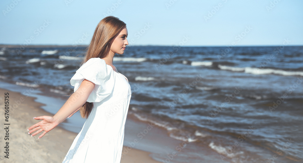 Happy smiling beautiful woman is on the ocean beach in a white summer dress, open arms Happy smiling beautiful woman is on the ocean beach in a white summer dress, open arms