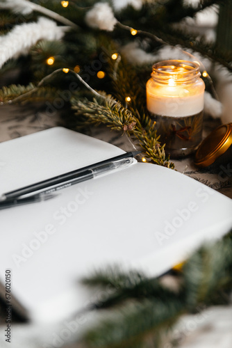 A bullet journal for planning and writing is laying open on the table with festive christmas tree branches.