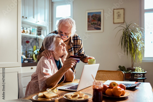 Senior couple online shopping with credit card and laptop from home photo