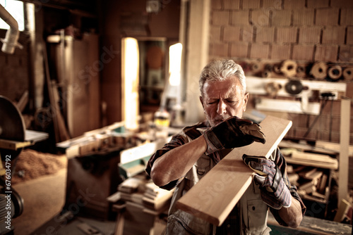 фотографія Senior carpenter selecting wood piece for project in workshop