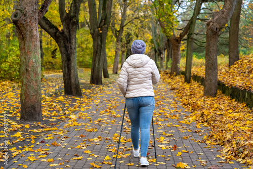 Mid-adult woman exercising Nordic walking in city park
