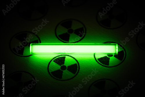 Tritium. Radioactive glow. Gaseous tritium light source in a glass vial. Radiation sign. Neon green glow hazards to employees, inspectors. Irradiated zone. Luminous fluorescence, phosphorescence  photo