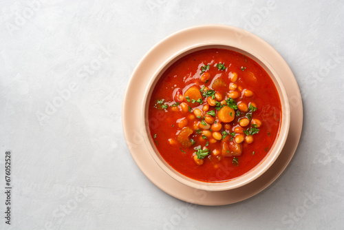 Greek bean soup Fasolada with tomatoes, carrot, celery and onion in bowl on concrete background photo