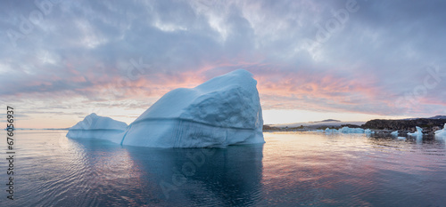 Arctic nature landscape with icebergs in Greenland icefjord with midnight sun. Early morning summer alpenglow during midnight season. Hidden Danger and Global Warming Concept. Tip of the iceberg.