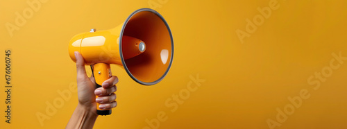 Hand holds megaphone on yellow background with copy space. Banner with loudspeaker for advertising ads