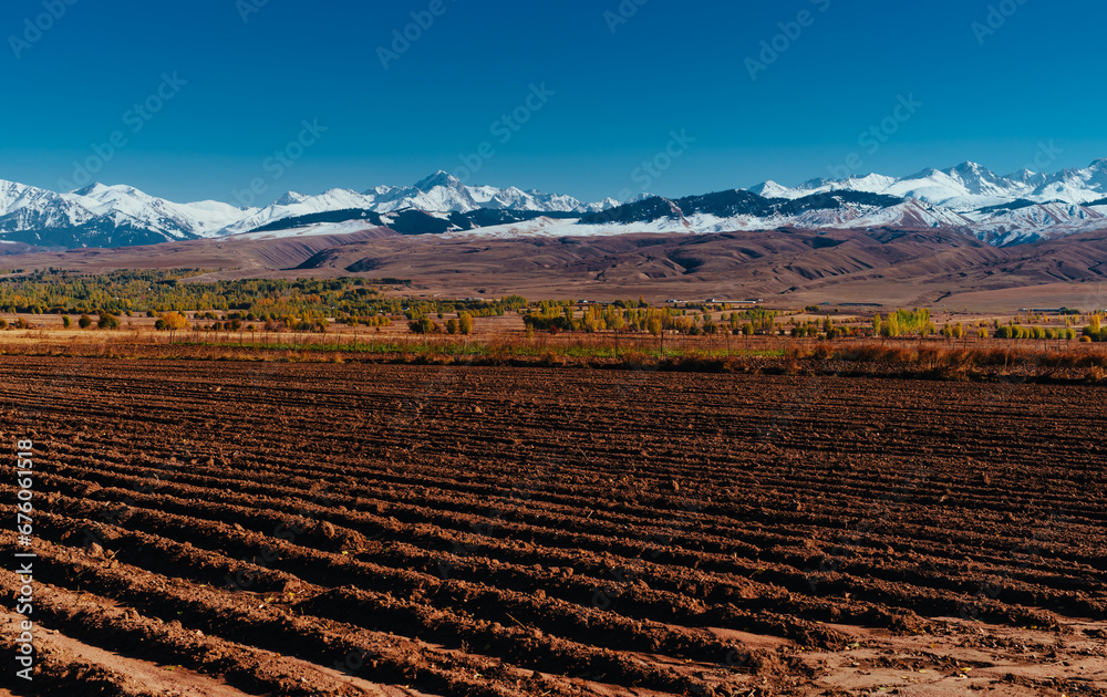 Autumn landscape with ploughed field on mountains background, Kyrgyzstan