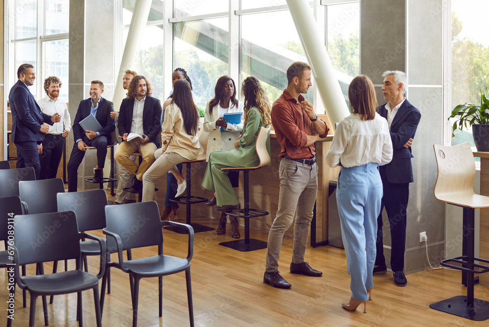 Full length photo of a group of diverse business people men and women chatting after meeting. Company employees or group of staff talking in modern office or conference room discussing work project. - obrazy, fototapety, plakaty 