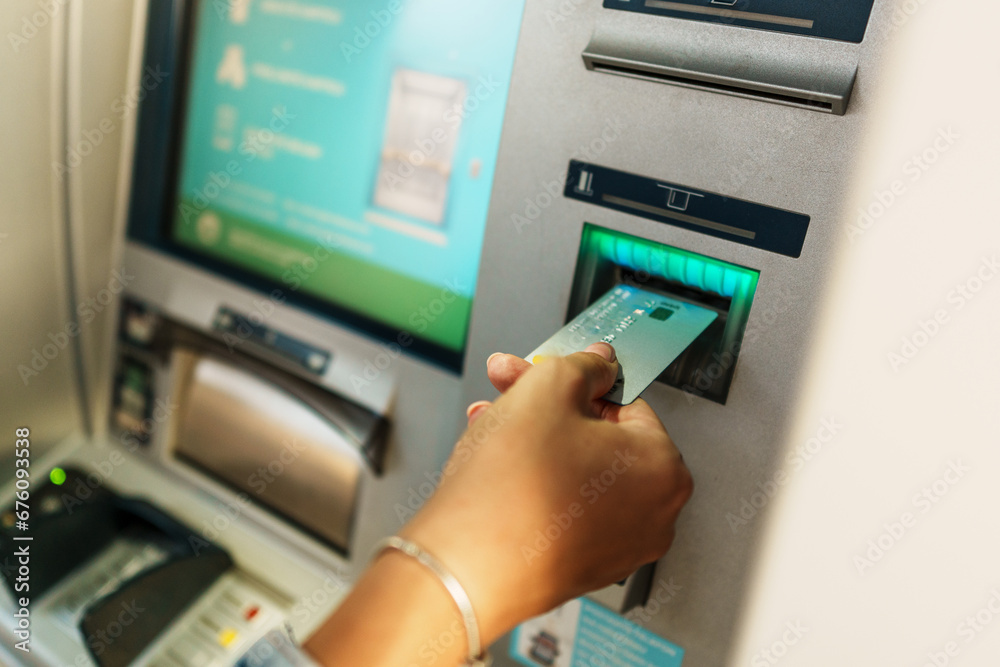 In a tightly framed shot, the woman's hands are shown while she inserts her card into the ATM and enters her PIN for secure access to her account. In a tightly framed shot, the woman's hands are shown while she inserts her card into the ATM and enters her PIN for secure access to her account.
