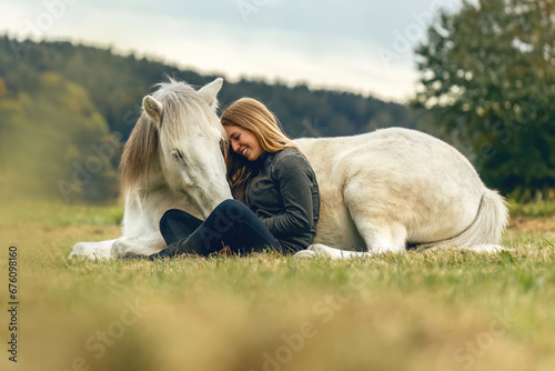 A young woman and her icelandic horse working and cuddle together, equestrian natural horsemanship concept photo