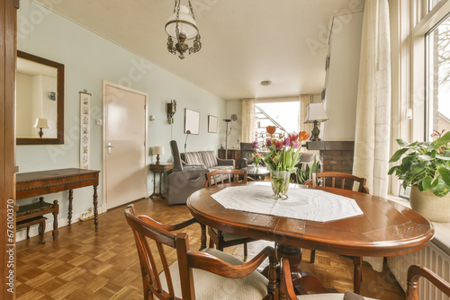 a dining room with wood flooring and wooden table in front of large window looking out onto the living room