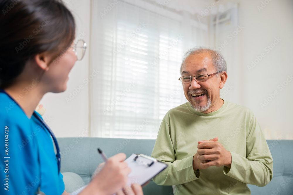 Obraz premium Asian young nurse writing prescription during home visit sick elder old man, Senior man takes doctor at home telling about health complaints, health care and medical concept