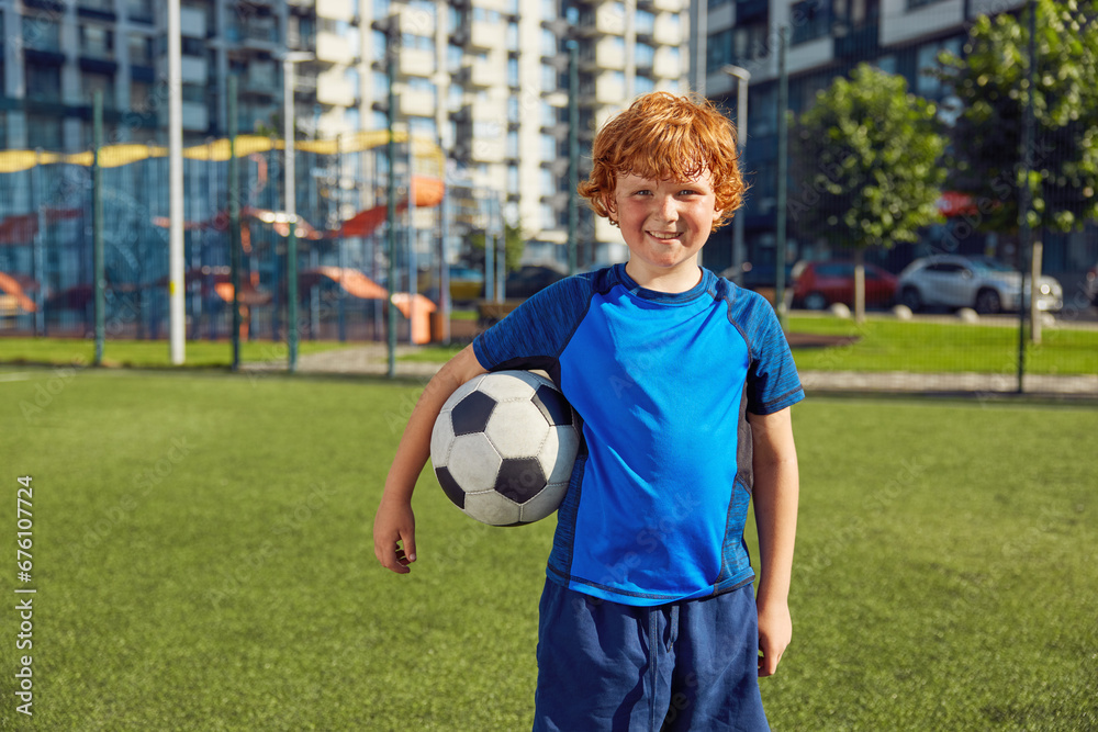 Cute redhead boy child wearing sportive uniform with soccer ball portrait Cute redhead boy child wearing sportive uniform with soccer ball portrait