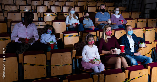 mother  father and their children sitting at film in auditorium during epidemic