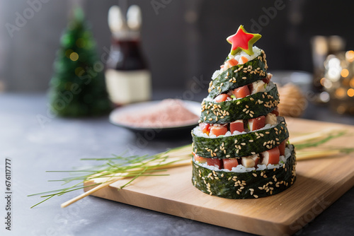 The concept of sushi on New Year night. Fresh sushi roll with salmon and avocado in a pyramid with Christmas decorations. Traditional japanese food. Sushi in form of christmas tree with copy space. photo