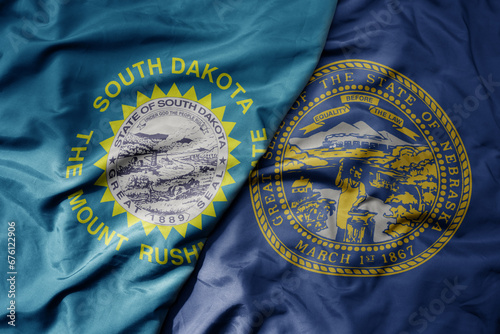 big waving colorful national flag of nebraska state and flag of south dakota state . photo