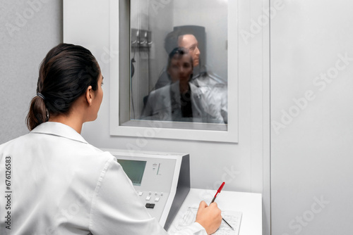 Audiologist woman doing the hearing exam to a mixed race man patient using an audiometer in a special audio room. Audiometric testing. Hearing loss treatment. photo