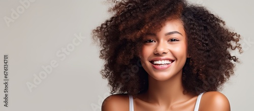The African woman with her beautiful curls stands against an isolated background in a fashionable spa showcasing her girl s natural beauty and radiant smile on her happy face in a captivati