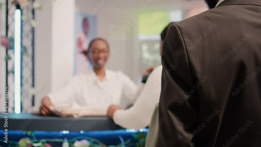 African american cashier processing items in elegant clothing shop at checkout counter for customers waiting in line. Employee assisting shoppers with their purchases, dolly out shot