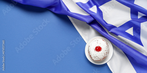 Traditional donut and flag of Israel on blue background with space for text. Hannukah celebration photo