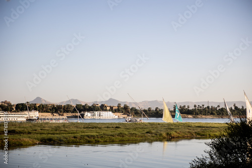 sail boats floating along the nile river with mountains in the distance in Luxor Egypt