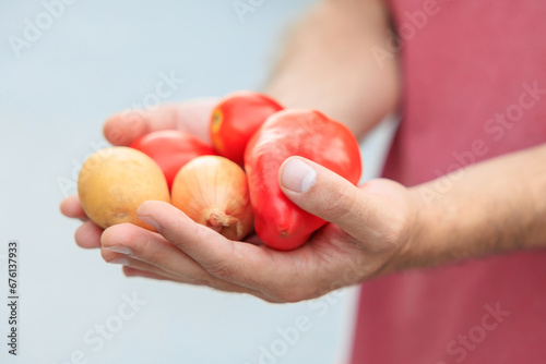 The guy's hand holds vegetables. Selective focus on hands with blurred background