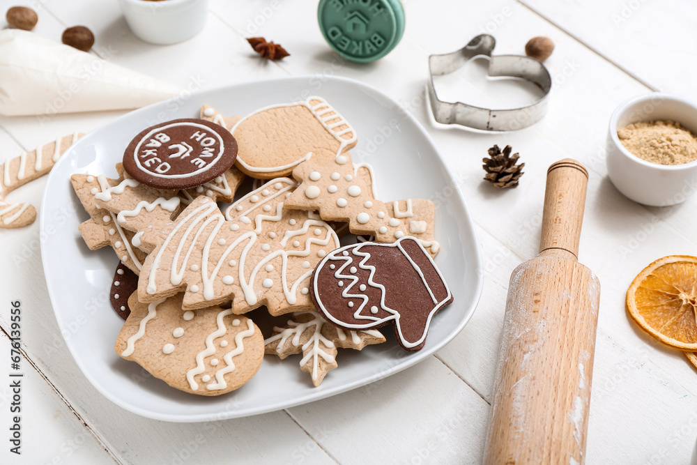 Plate with tasty Christmas cookies and utensils on light wooden table Plate with tasty Christmas cookies and utensils on light wooden table