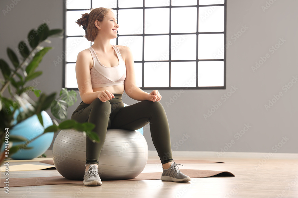 Beautiful young woman in sportswear sitting on fitness ball at gym Beautiful young woman in sportswear sitting on fitness ball at gym