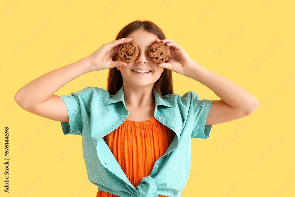 Happy girl holding sweet chocolate cookies on yellow background Happy girl holding sweet chocolate cookies on yellow background