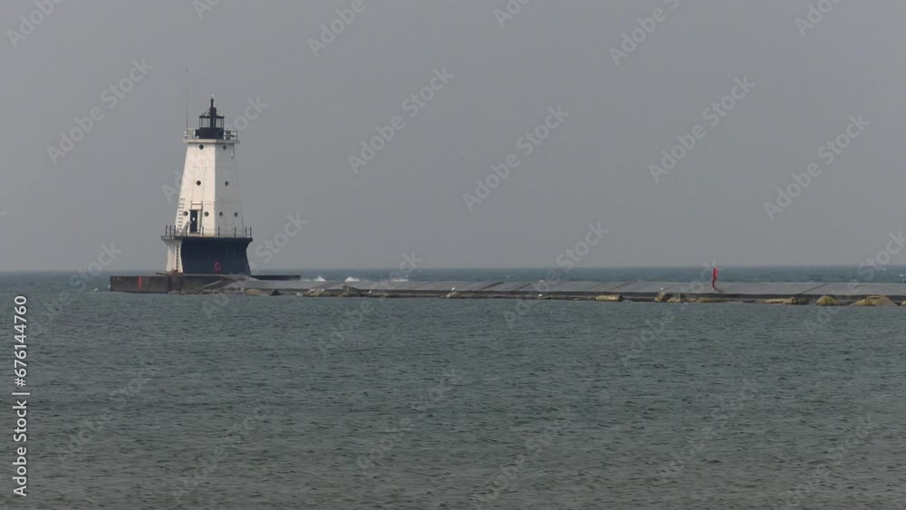 Ludington lighthouse on Lake Michigan. Very wide shot to show the heavy waves breaking on the pier on a very windy day. Shot on a very smoky day due to Canadian wildfire smoke that had moved in. Ludington lighthouse on Lake Michigan. Very wide shot to show the heavy waves breaking on the pier on a very windy day. Shot on a very smoky day due to Canadian wildfire smoke that had moved in.