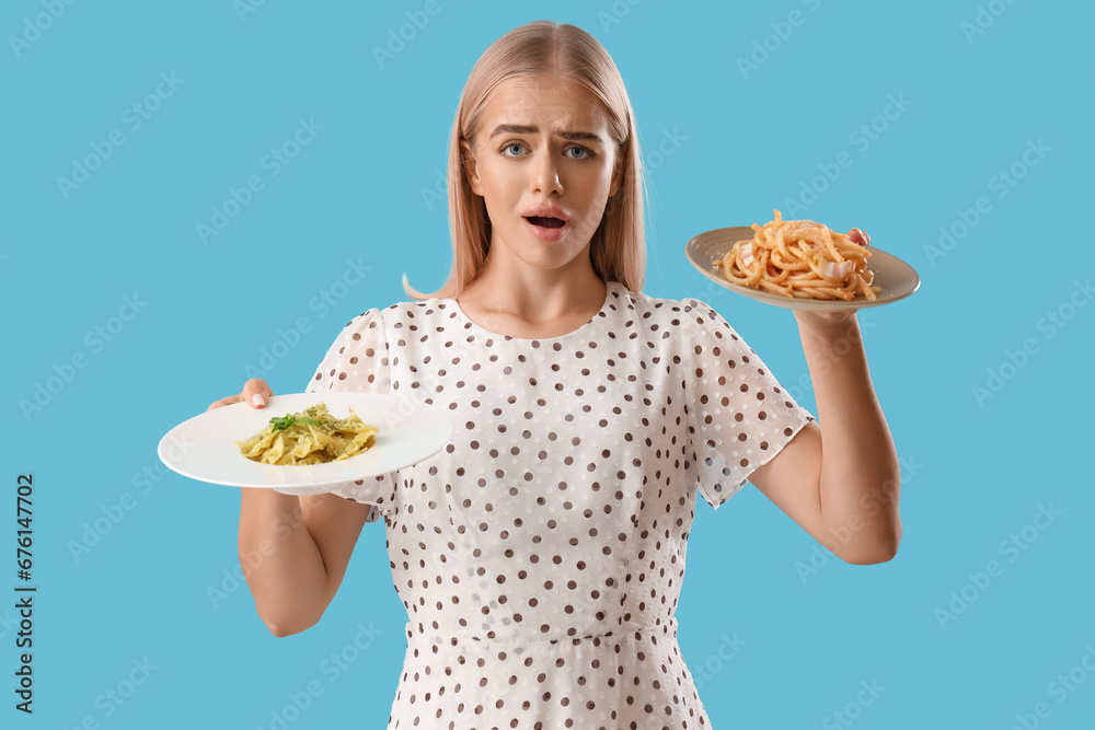 Confused young woman with tasty pasta on blue background Confused young woman with tasty pasta on blue background