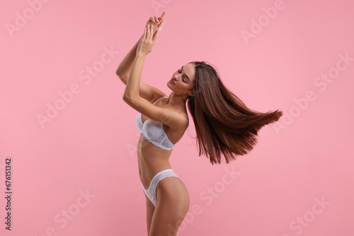 Young woman in elegant white underwear on pink background