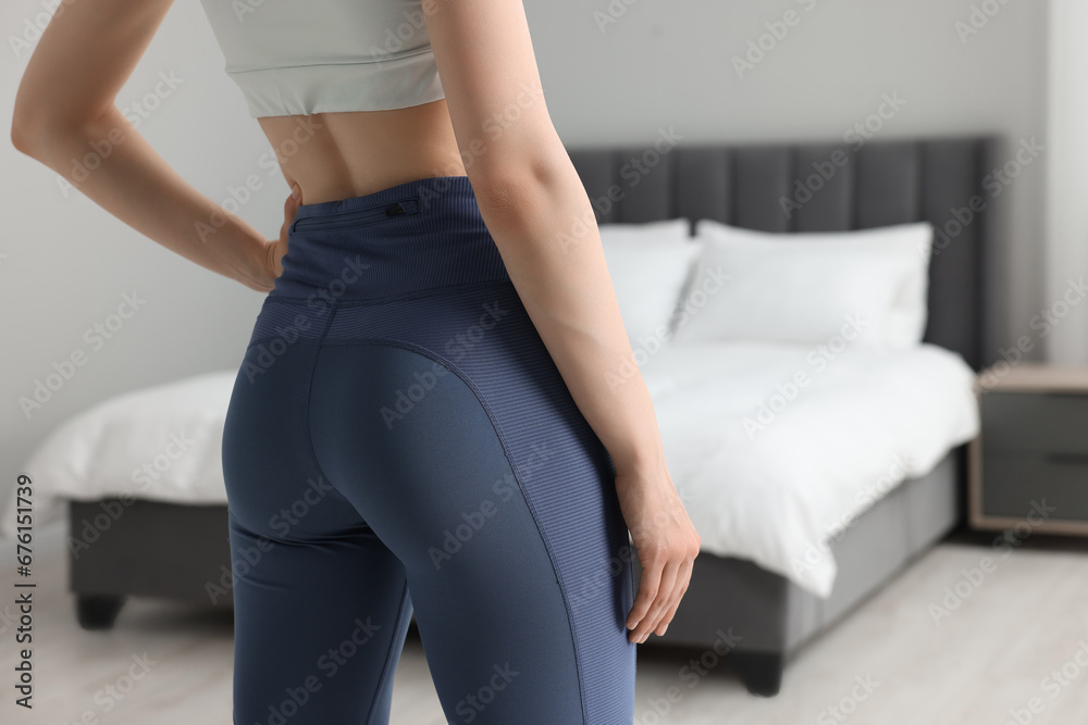 Woman wearing sportswear in bedroom, closeup. Space for text