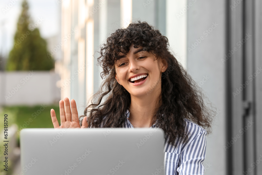 Happy young woman using modern laptop for video call outdoors Happy young woman using modern laptop for video call outdoors