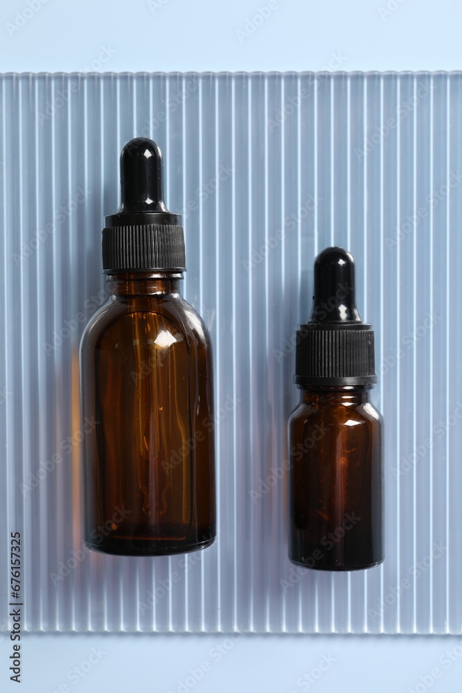 Bottles of cosmetic serum on light blue background, top view Bottles of cosmetic serum on light blue background, top view