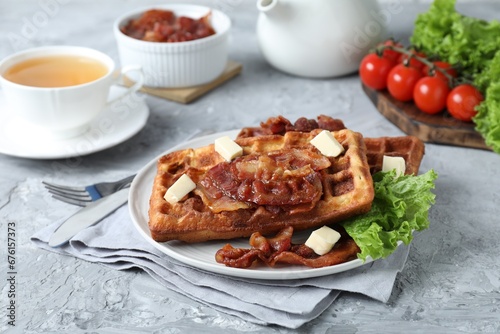 Delicious Belgium waffles served with fried bacon and butter on grey table