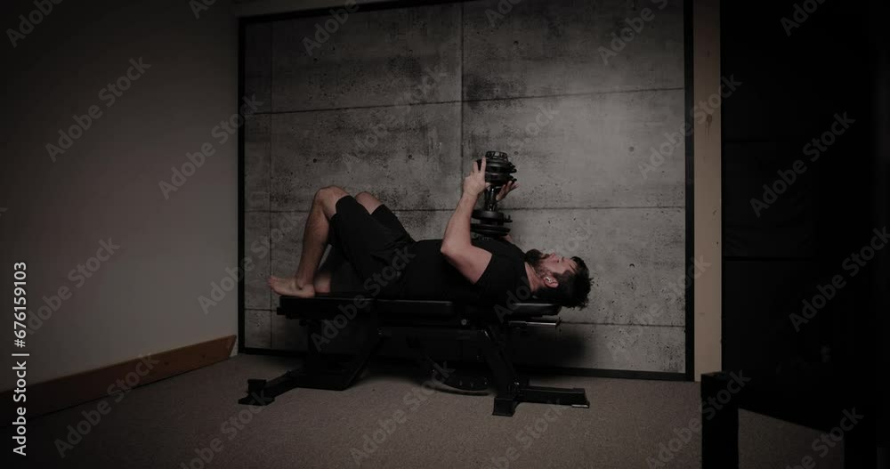 Lying skull crusher tricep extension, cinematic lighting, white man dressed in black gym attire. Lying skull crusher tricep extension, cinematic lighting, white man dressed in black gym attire.