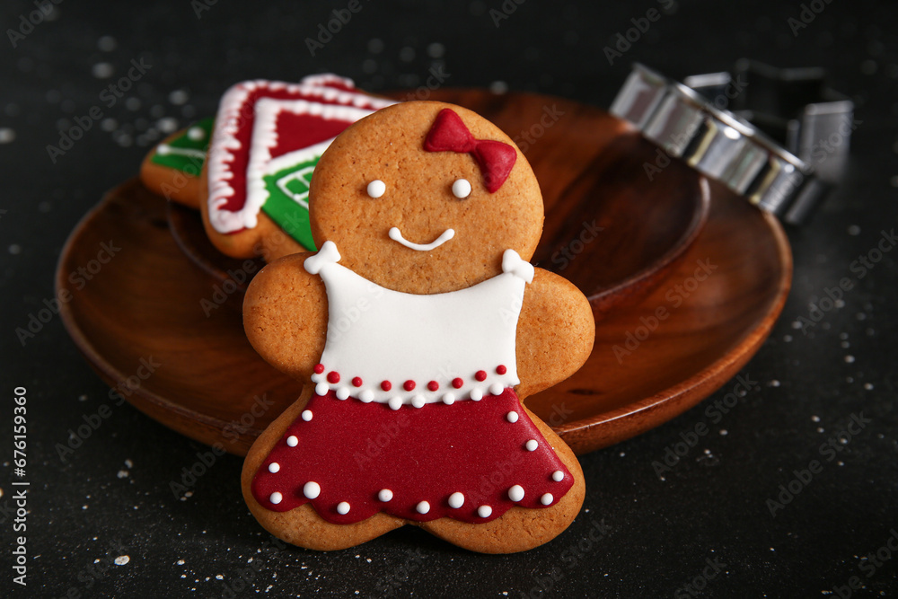 Tasty Christmas cookie in shape of girl on black grunge background