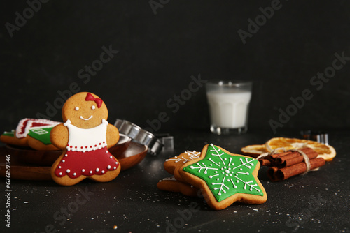 Tasty Christmas cookies and glass of milk on table against black grunge background